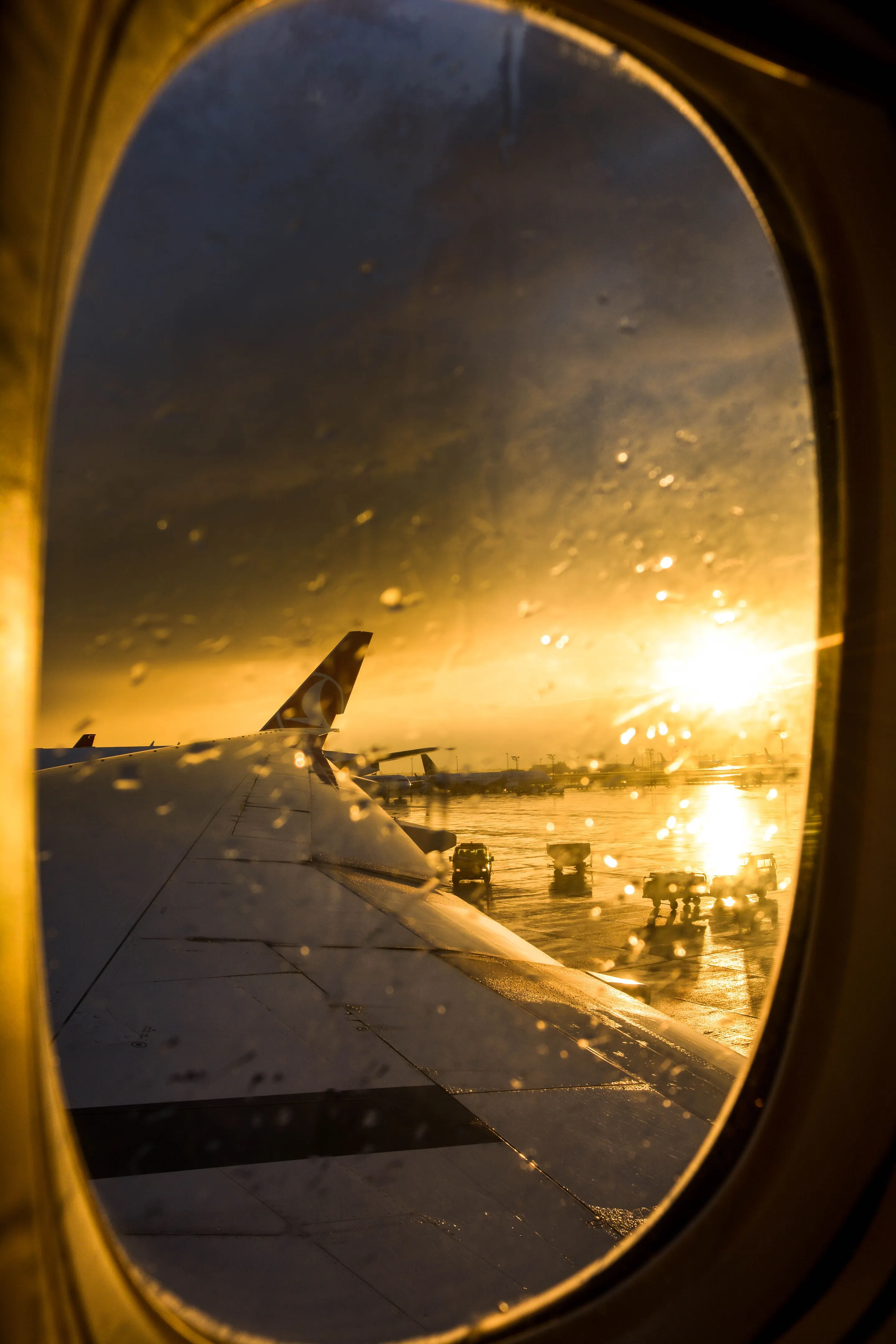 Sunset through an aircraft window at Ezeiza with the wing in view.