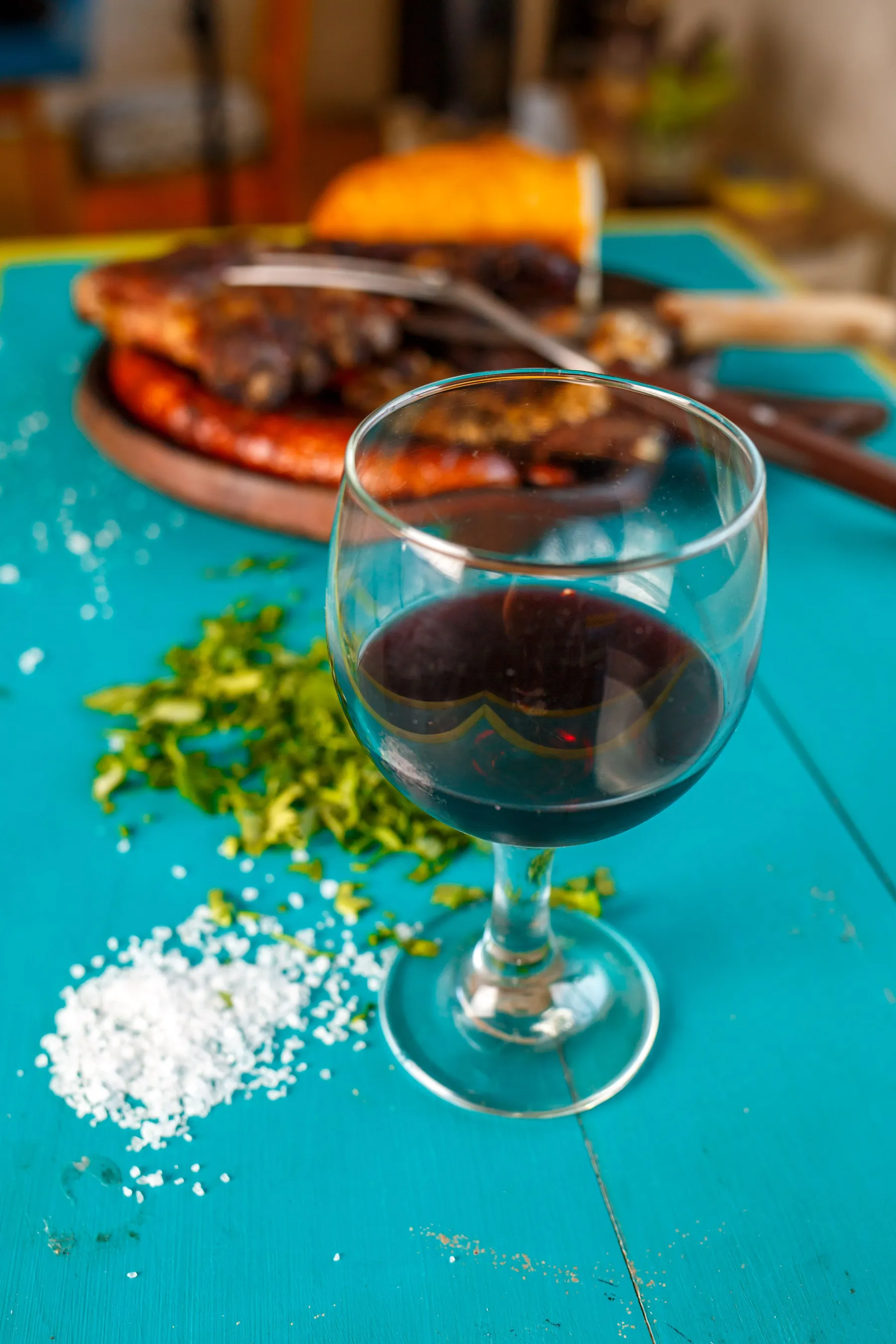 A close view of red wine beside an Argentine barbecue meal