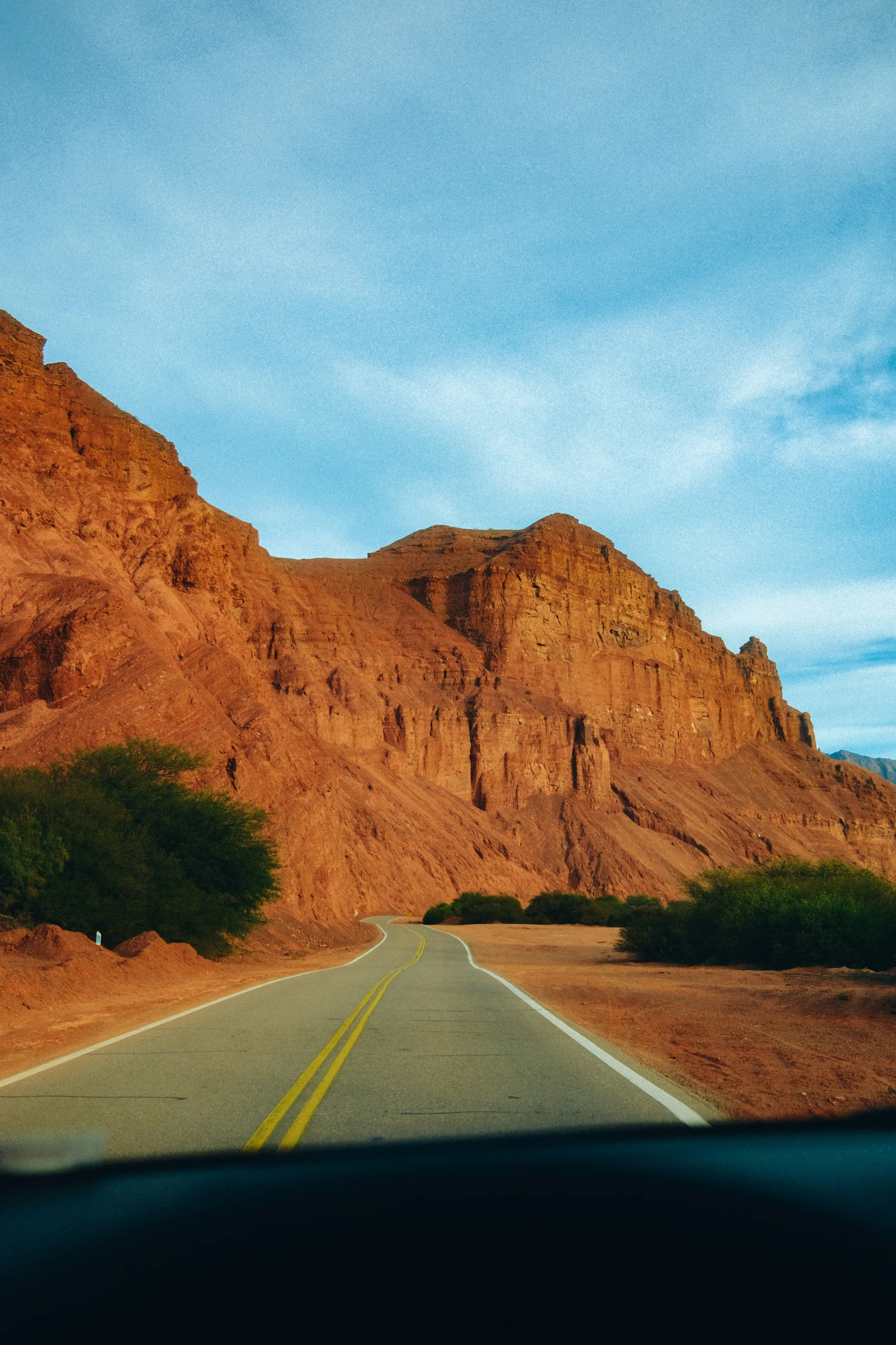 A road approaching a towering rock wall in the Cafayate landscape.