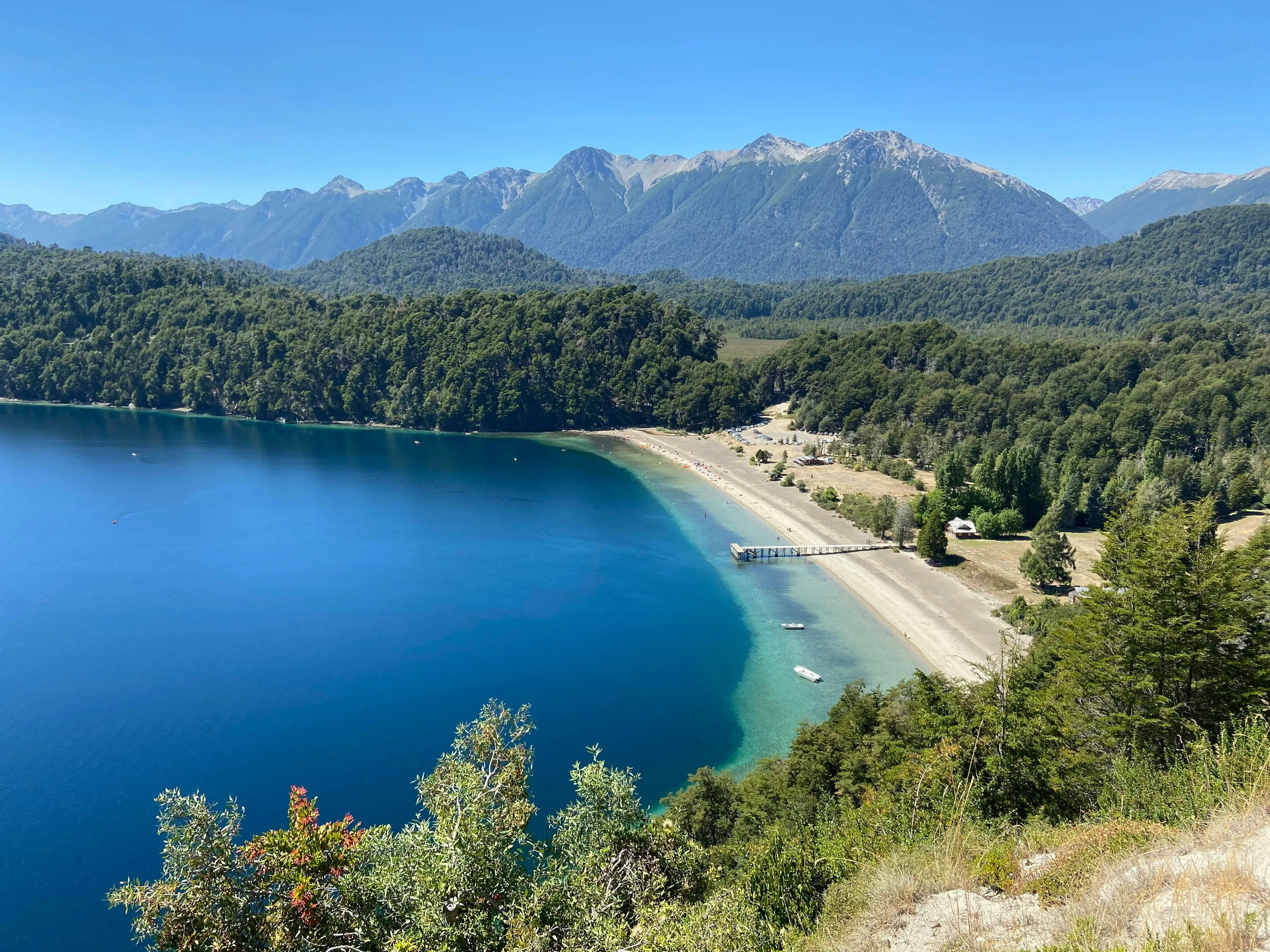 Green forest beside the blue water of Lago Espejo.