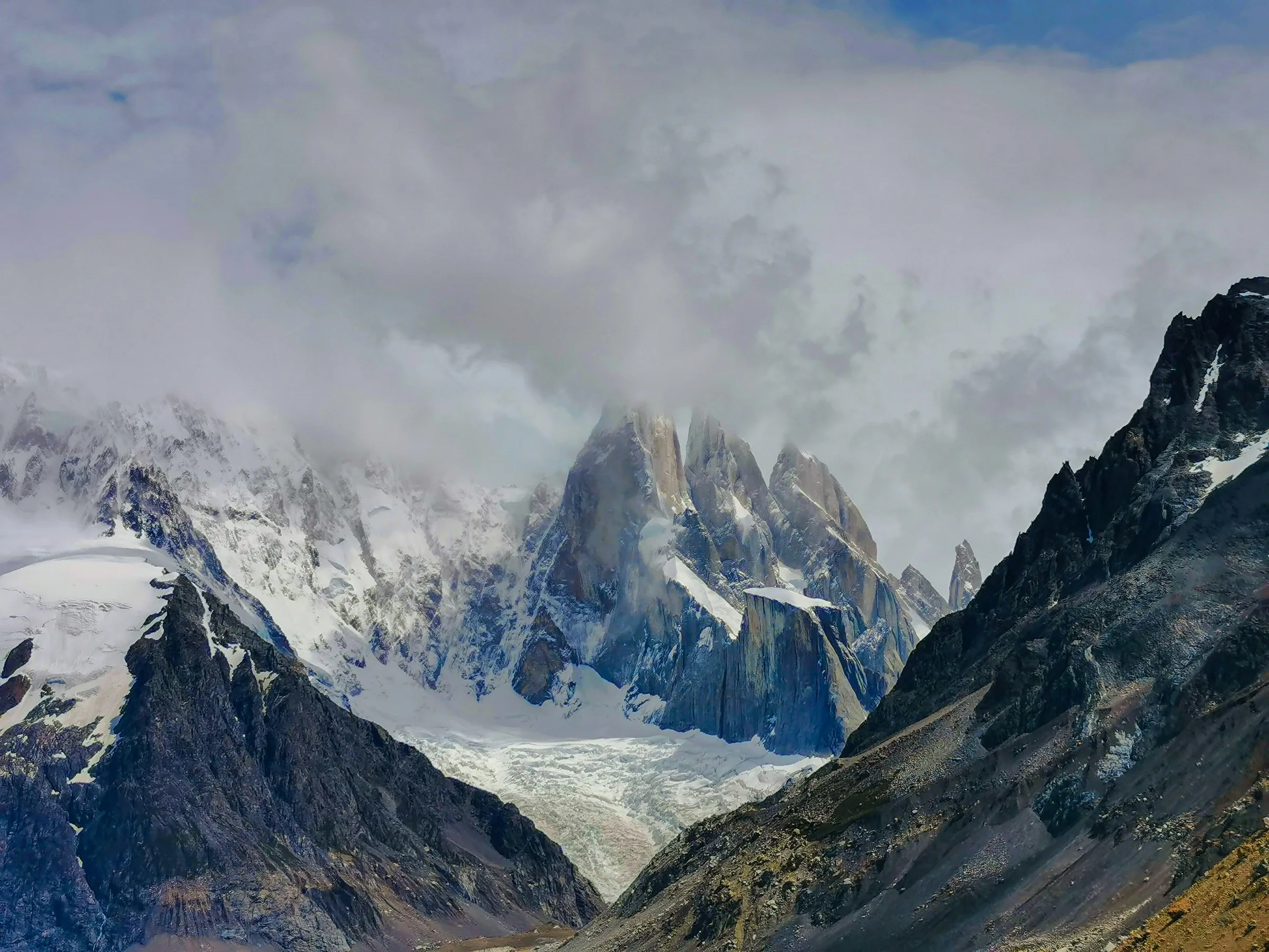 Snowy mountains beneath a cloudy sky along the Torre valley approach