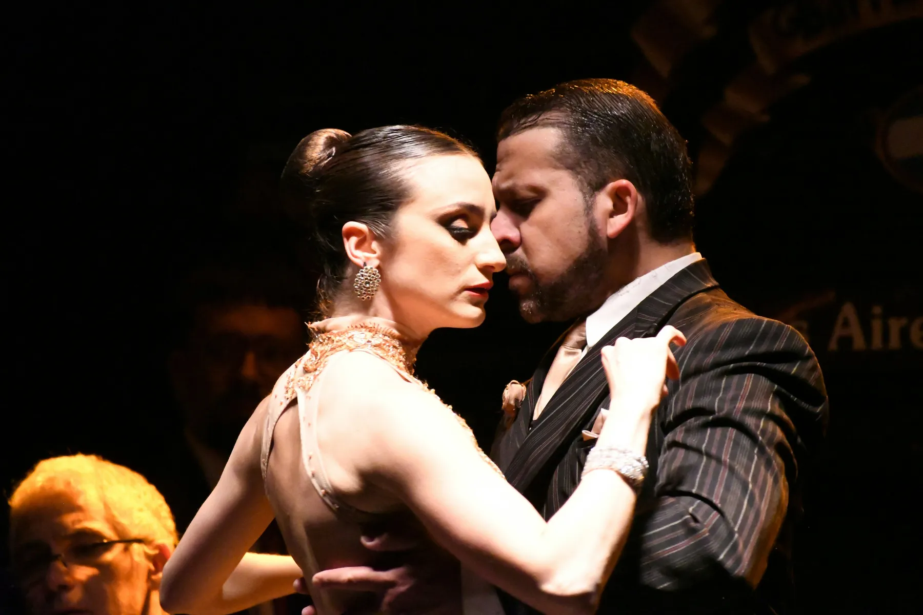 A couple performing tango under warm stage lighting at La Ventana