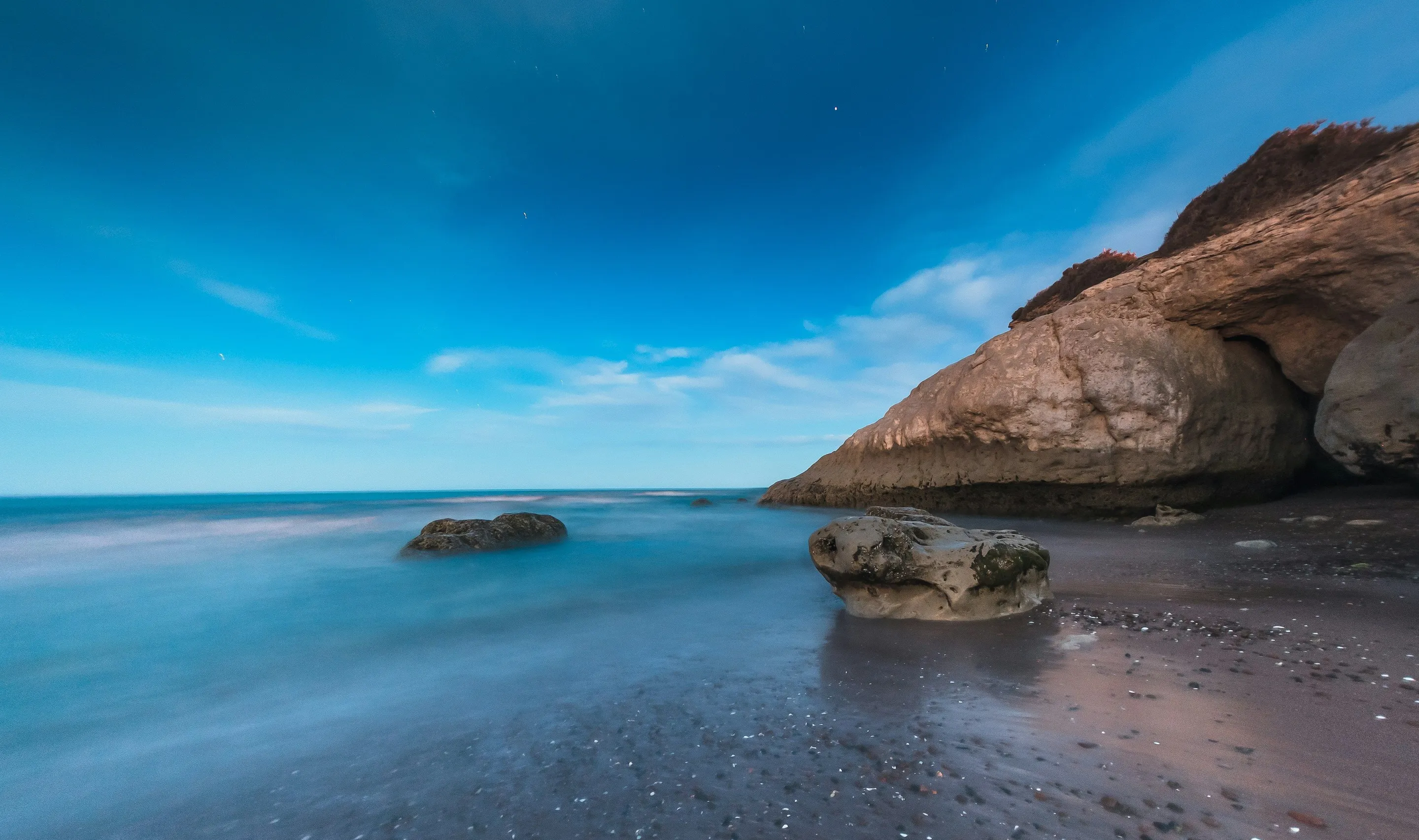 Rocky coastal formations beside blue water near Puerto Madryn