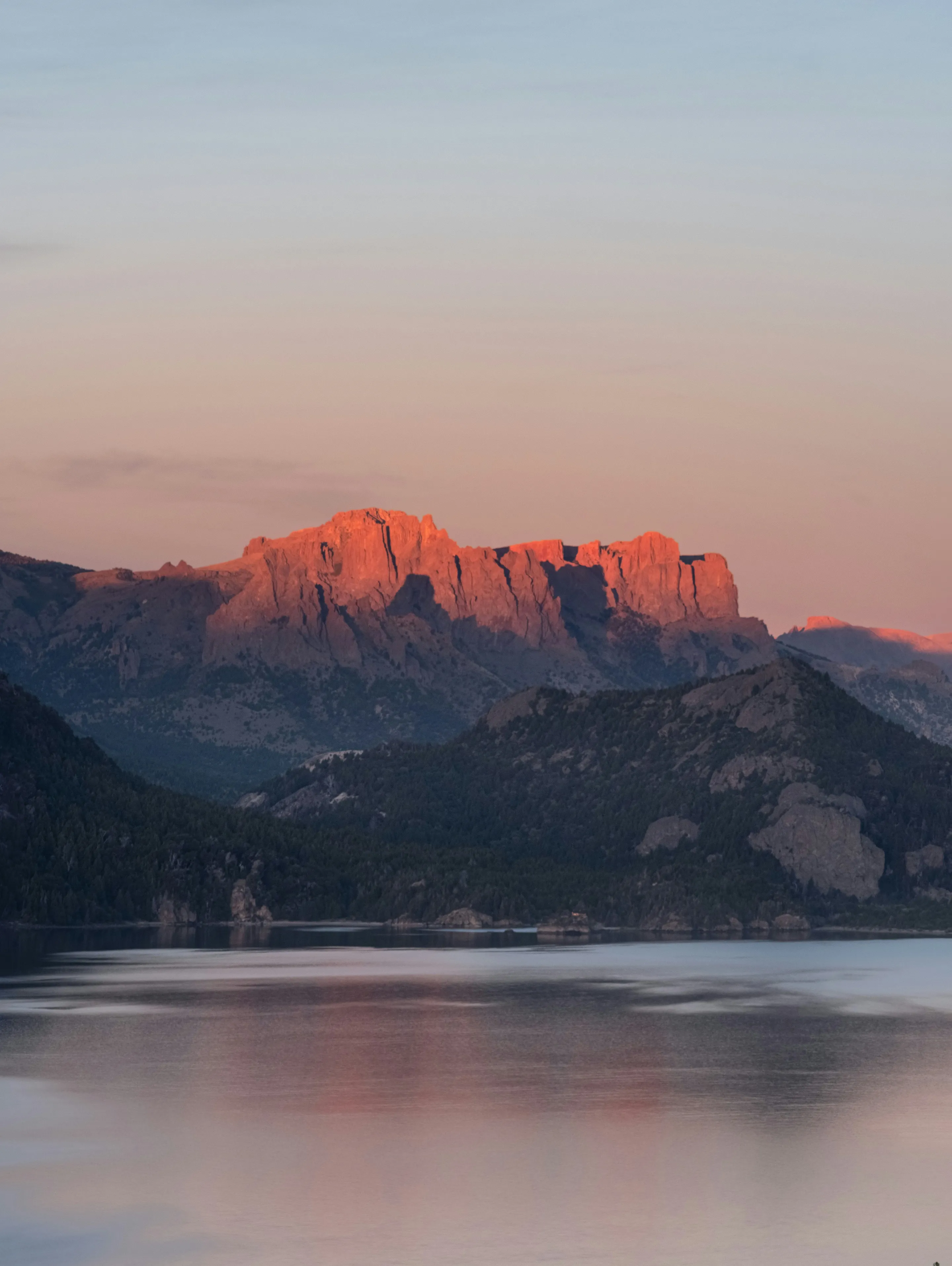 Sunset light spilling across Lake Traful and layered mountain silhouettes