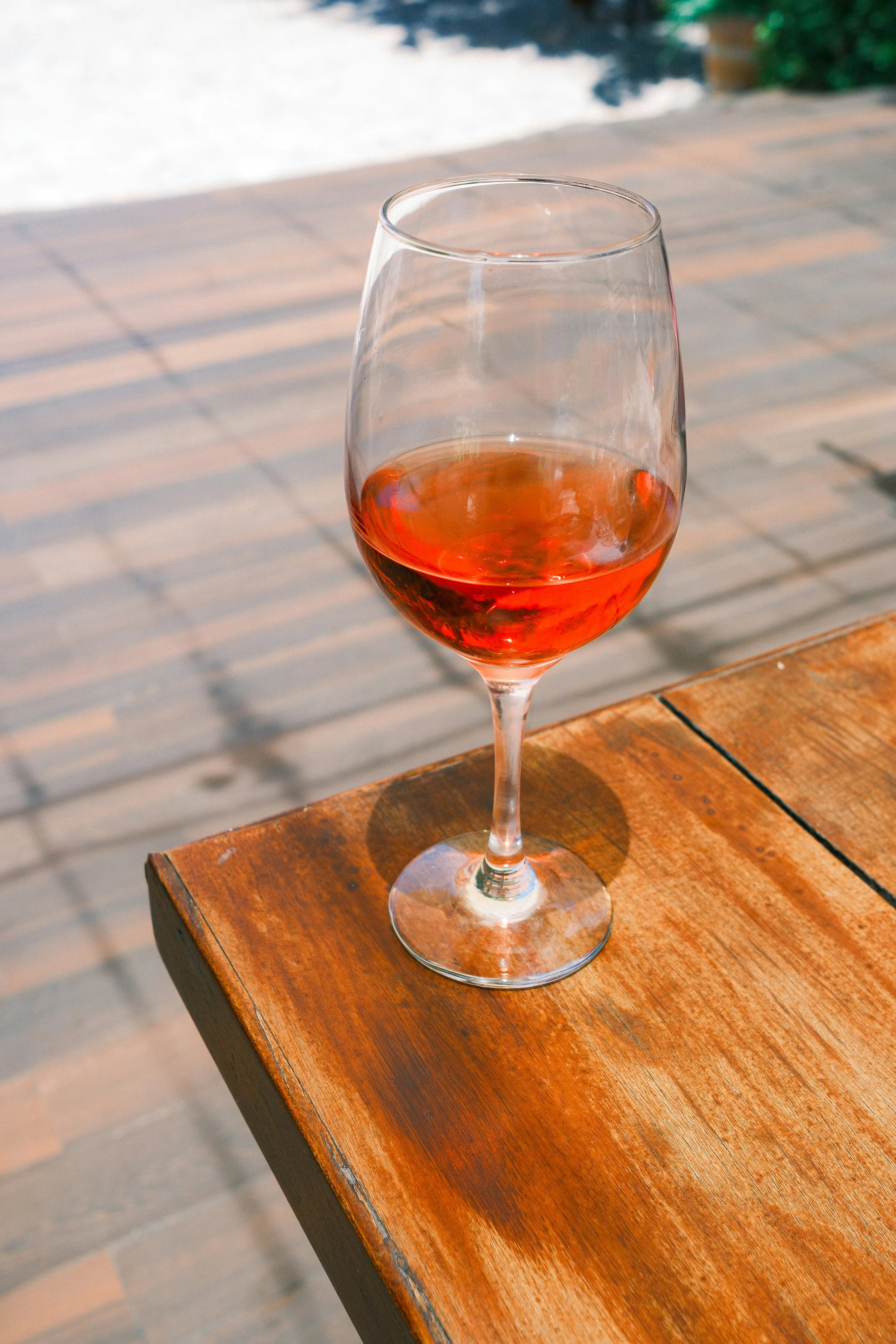 A glass of rosé wine on a wooden table.