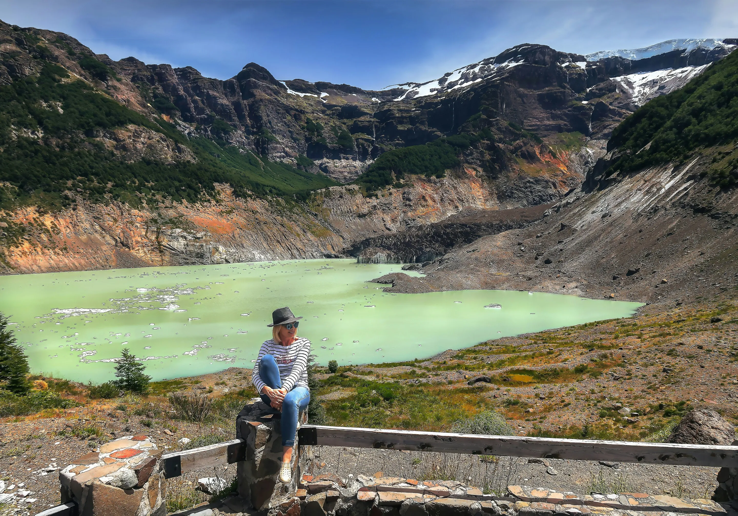 A traveller beside vivid green glacial water beneath Cerro Tronador