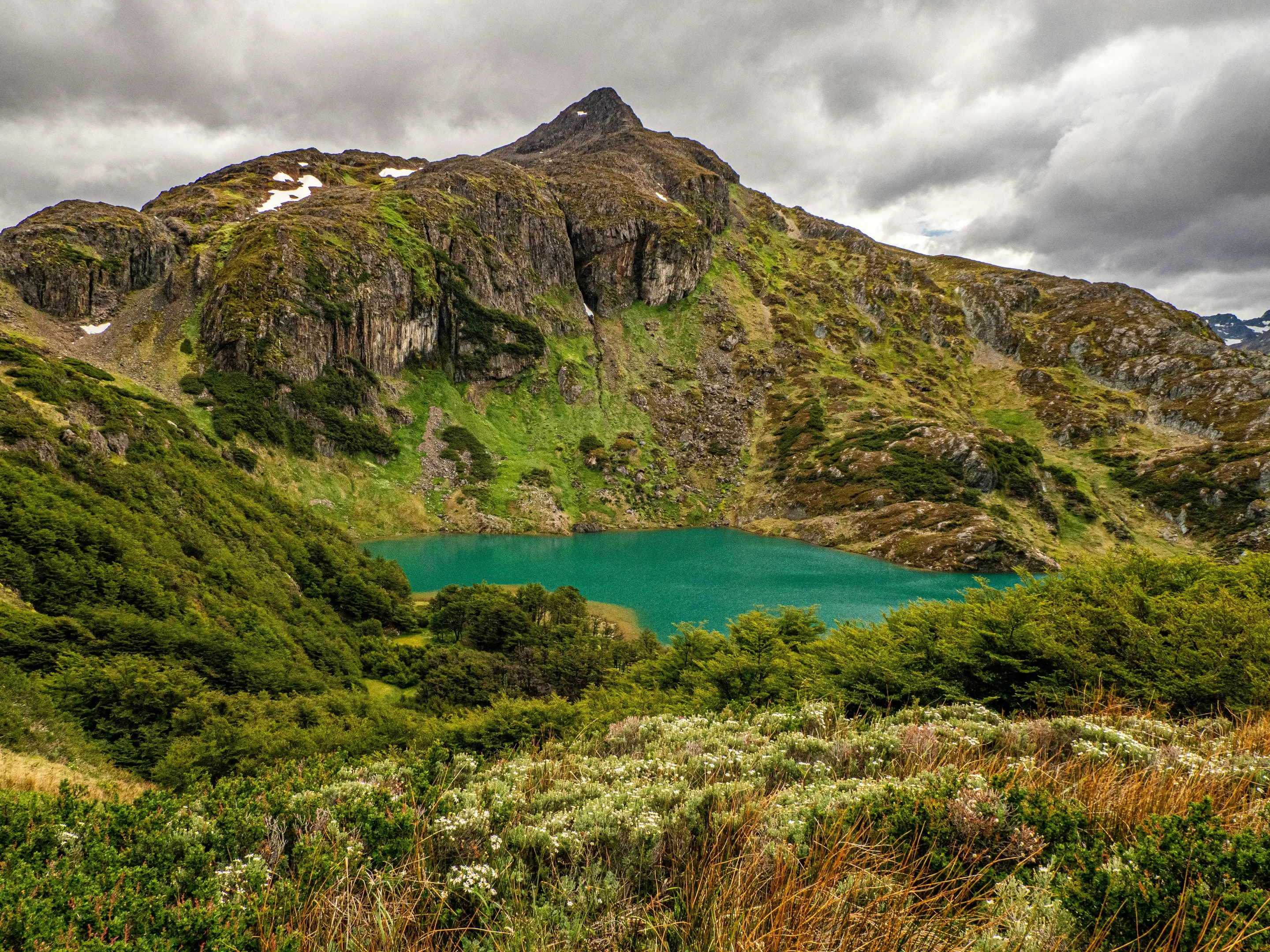 Mountain slopes and green vegetation above water in Tierra del Fuego National Park.