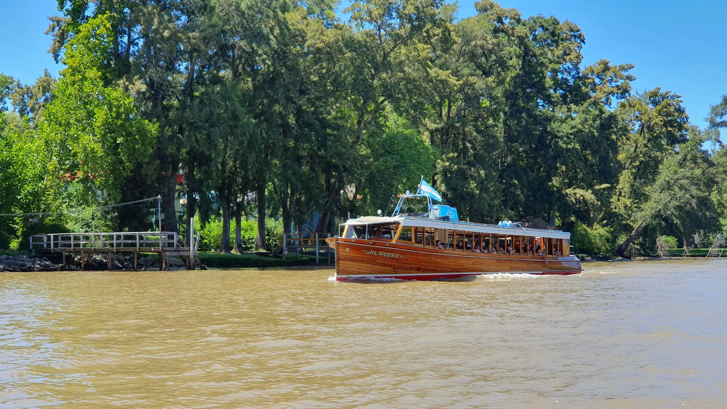 A passenger boat beside the wooded banks of the Tigre Delta
