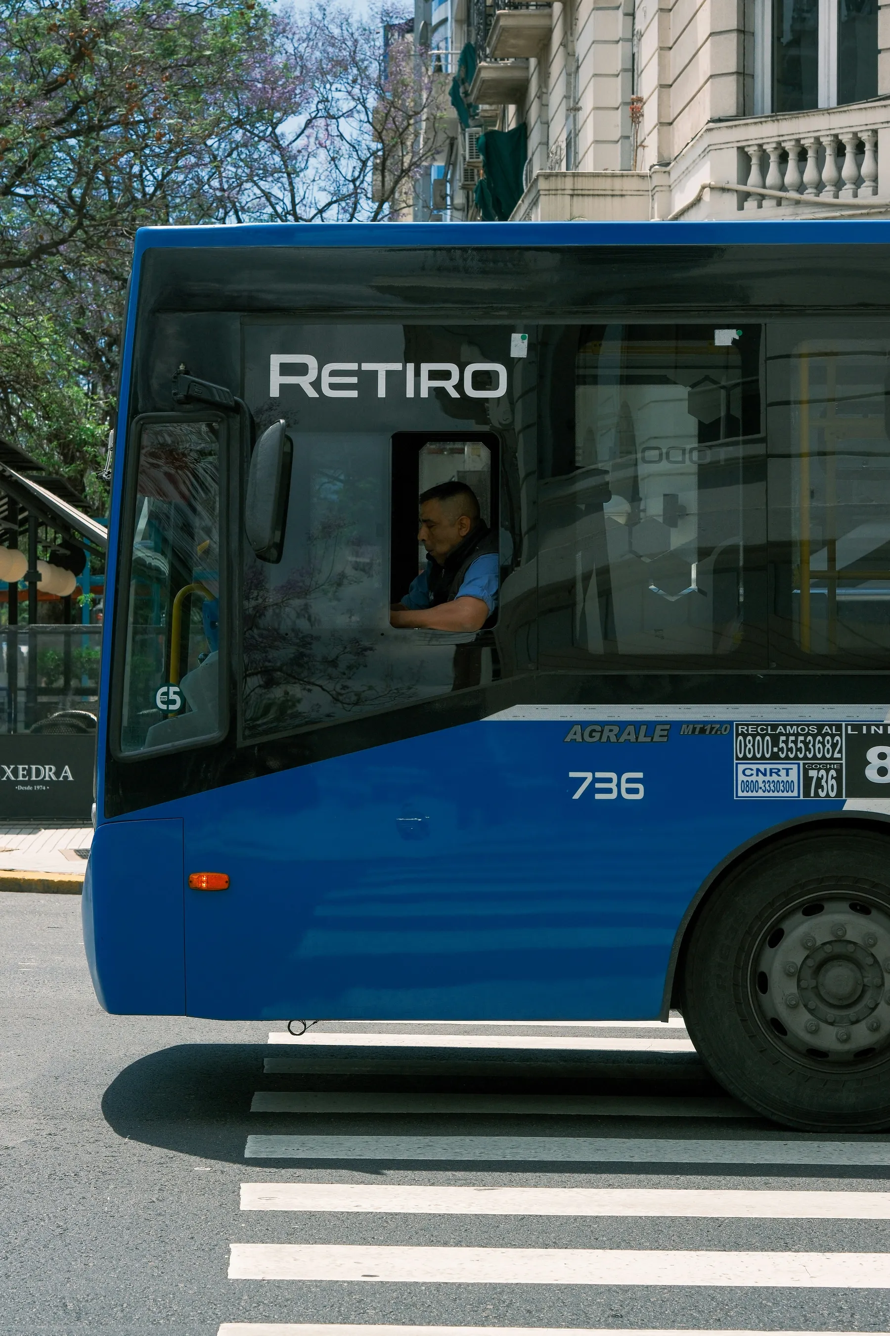 A driver looking from the window of a blue Buenos Aires city bus.