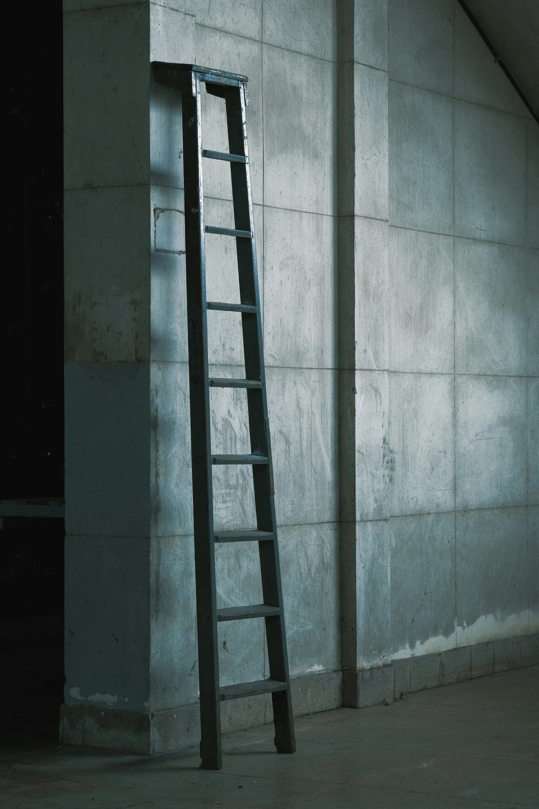 A blue ladder against a textured wall in Chacarita Cemetery